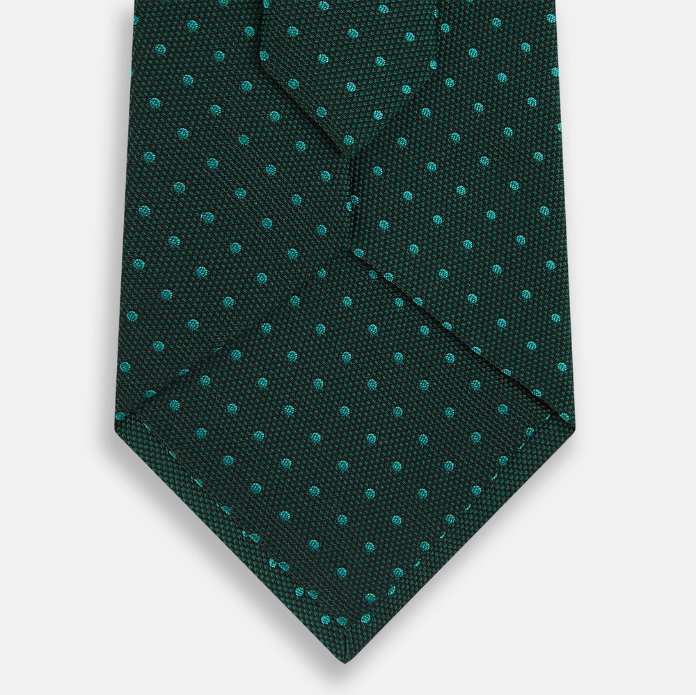 The Turnbull & Asser Dark Green Micro Dot Silk Tie features a refined pattern of light blue micro dots, making it the perfect accessory for any occasion.