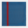 View 3 of product A blue silk pocket square by Turnbull & Asser, featuring thin black stripes, a striking vertical red stripe, and a turned-over corner that reveals the reverse side. The brand name is printed discreetly in one corner.
