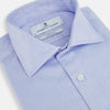 View 2 of product The Turnbull & Asser BLUE HERRINGBONE TAILORED FIT SHIRT WITH KENT COLLAR features long sleeves and buttoned cuffs, offering a timeless formal look in a classic light blue herringbone fabric, laid flat on a white background.