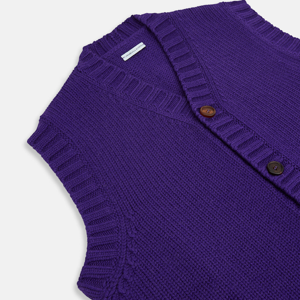 The Turnbull & Asser Purple Merino V-Neck Sleeveless Cardigan features a ribbed collar, button-down front, and two pockets—a refined light layer for gentlemen—shown on a plain white background.
