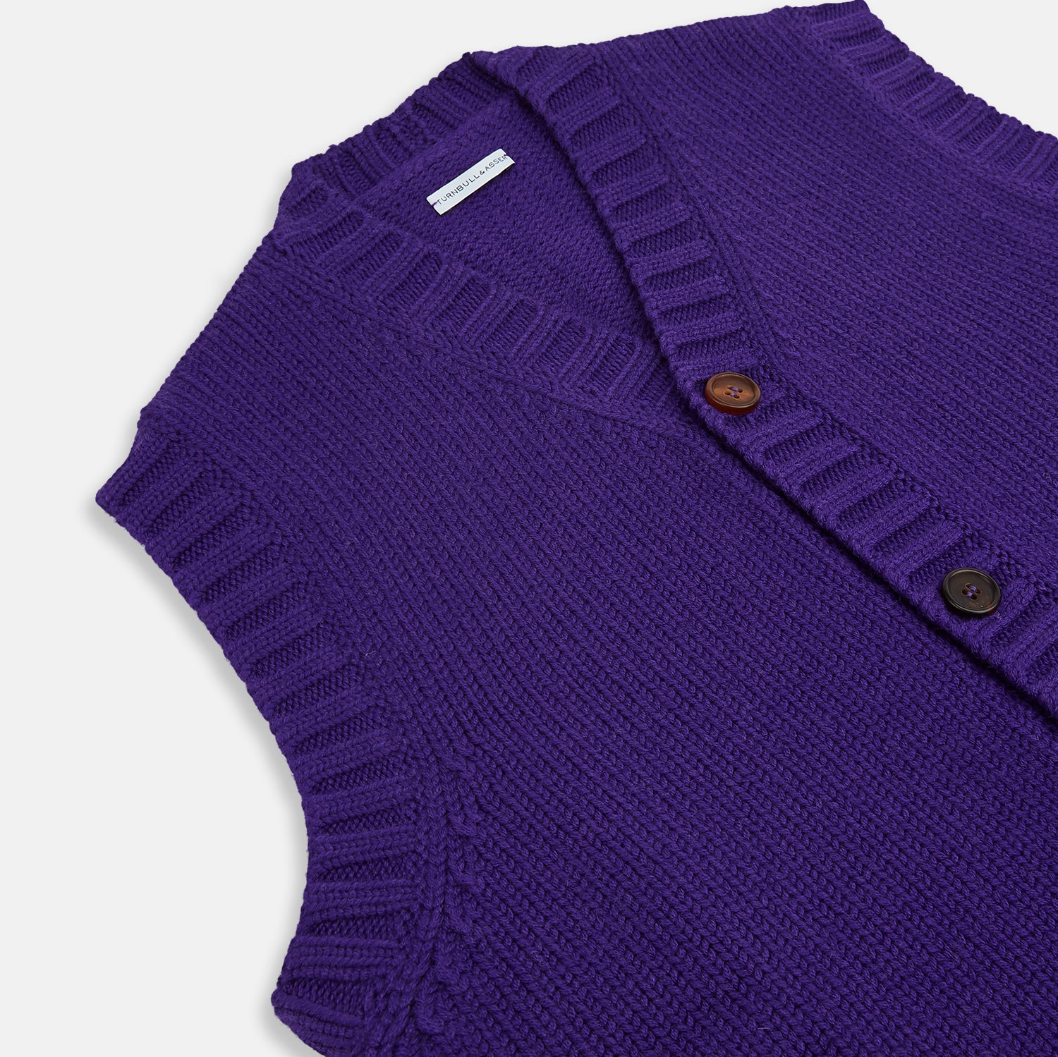 View 2 of product The Turnbull & Asser Purple Merino V-Neck Sleeveless Cardigan features a ribbed collar, button-down front, and two pockets—a refined light layer for gentlemen—shown on a plain white background.
