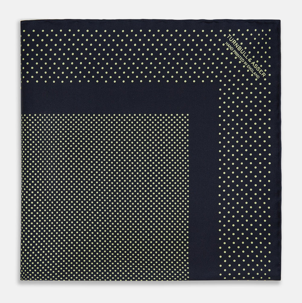 The Turnbull & Asser Navy and Gold Silk Pocket Square is handmade, featuring small gold polka dots on navy with a solid border, displayed neatly folded with one corner turned up.