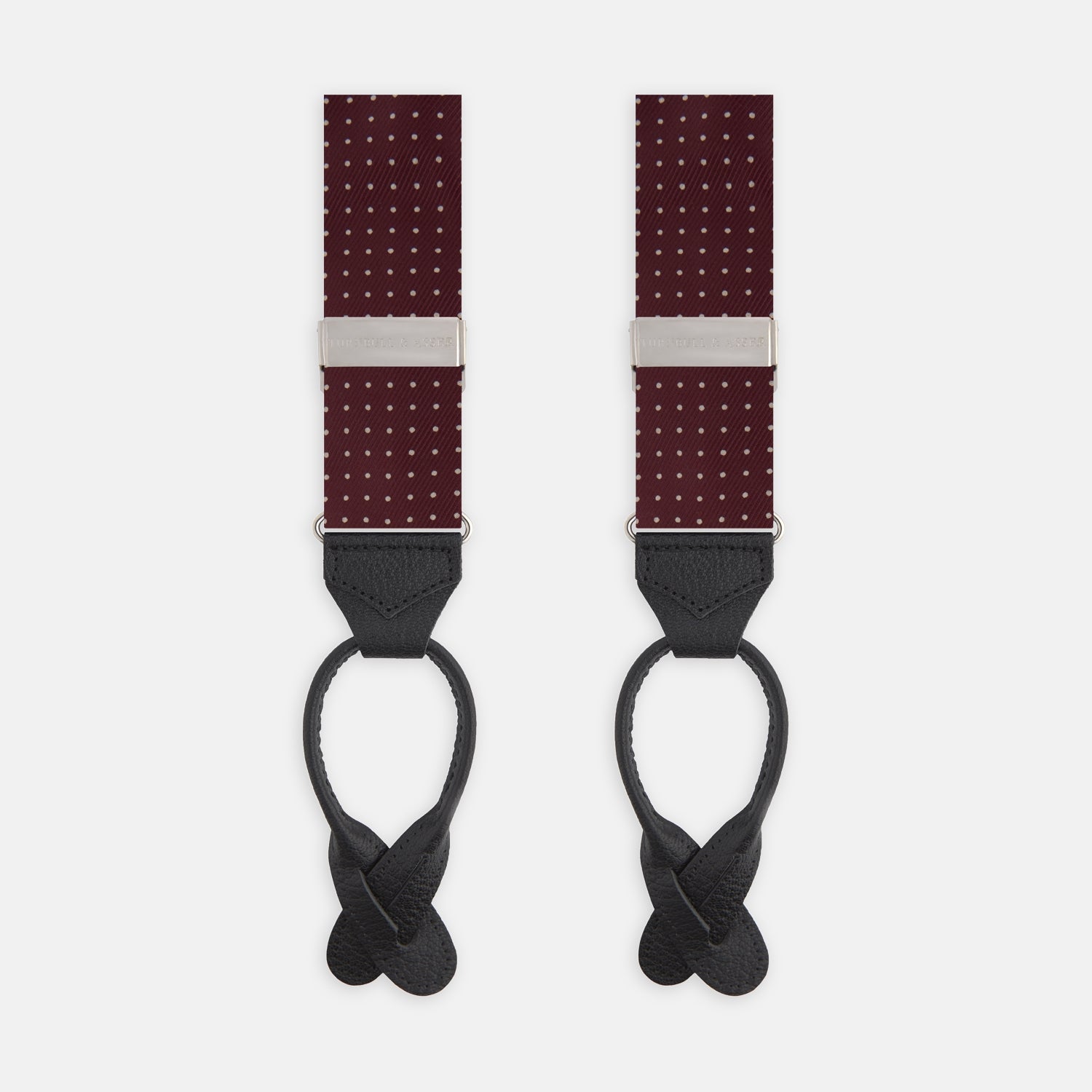 View 1 of product Turnbull & Asser Burgundy Small Spot Adjustable Silk Braces, featuring small white dots, black leather ends, and silver clasps, are displayed vertically on a plain white background for refined sartorial style.