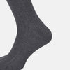 View 4 of product The Ash Long Sock by Turnbull & Asser is a single, knee-high sock in dark gray Egyptian cotton with a ribbed texture, displayed upright against a plain white background.