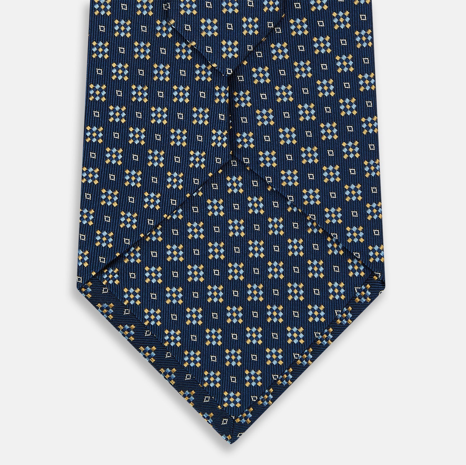 View 3 of product The Navy Diamond Silk Tie by Turnbull & Asser features a British-inspired geometric diamond pattern with small yellow and white squares against a navy silk background.