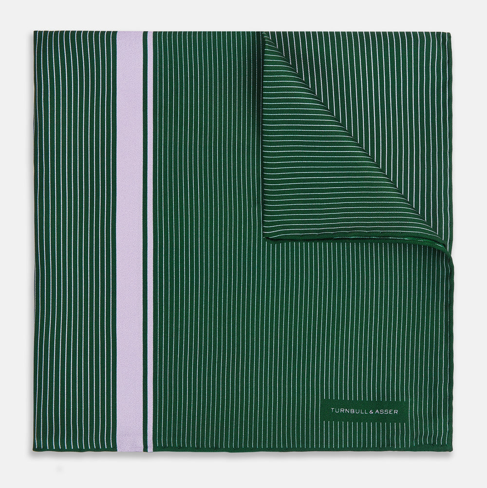 The Forest Green and Lilac Stripe Silk Pocket Square by Turnbull & Asser features thin white pinstripes, a bold light purple vertical stripe, and a visible branded label for classic British elegance. One corner is neatly folded over.