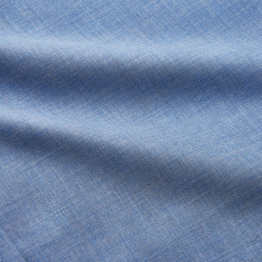 The Turnbull & Asser Blue Cotton Weekend Fit Blake Shirt features a light blue color, long sleeves, stand collar, white buttons, and a curved hem—ideal for casual weekends. Laid flat on a white background.
