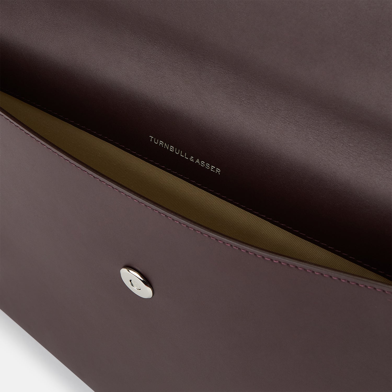 View 3 of product The Turnbull & Asser Burgundy Leather Snap-Fasten Pouch is a sleek, envelope-style laptop accessory with a smooth finish, curved flap, and elegant snap closure, ideal for business travel against a white background.
