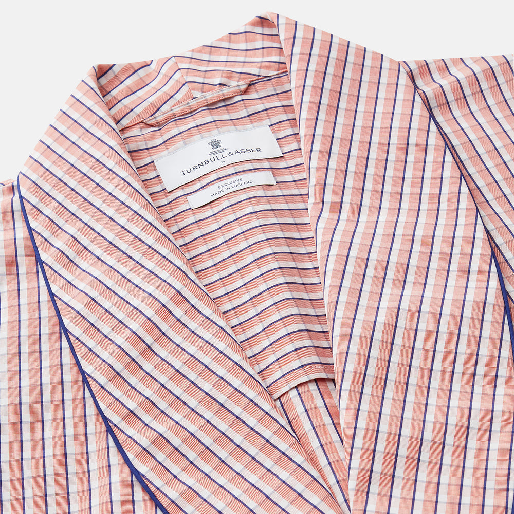 The Turnbull & Asser Orange Multi Check Cotton Arnold Gown features long sleeves, a shawl collar, wrap-around belt, and dark piping on the edges and pocket, displayed flat on a white background.