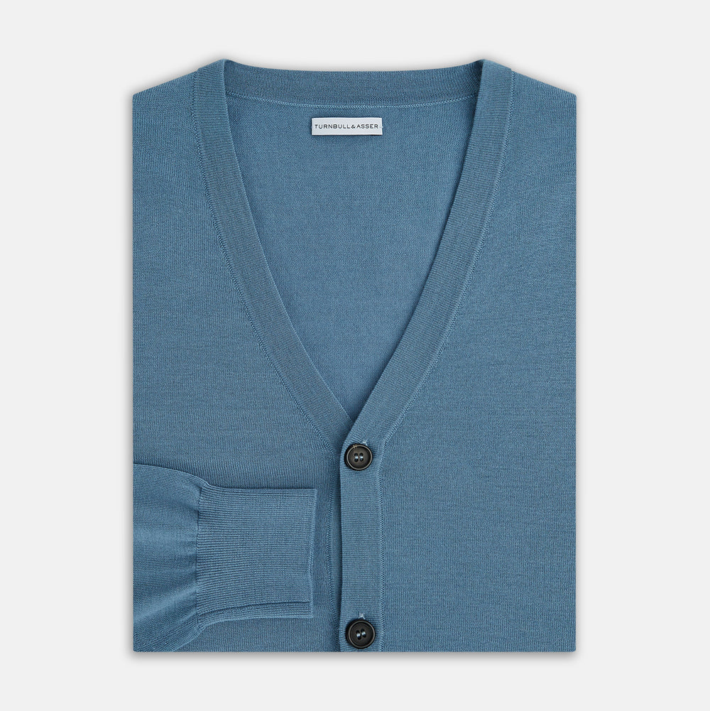 The Turnbull & Asser Pale Blue Fine Merino V-Neck Cardigan features long sleeves and five black buttons, showcased on a plain white background.