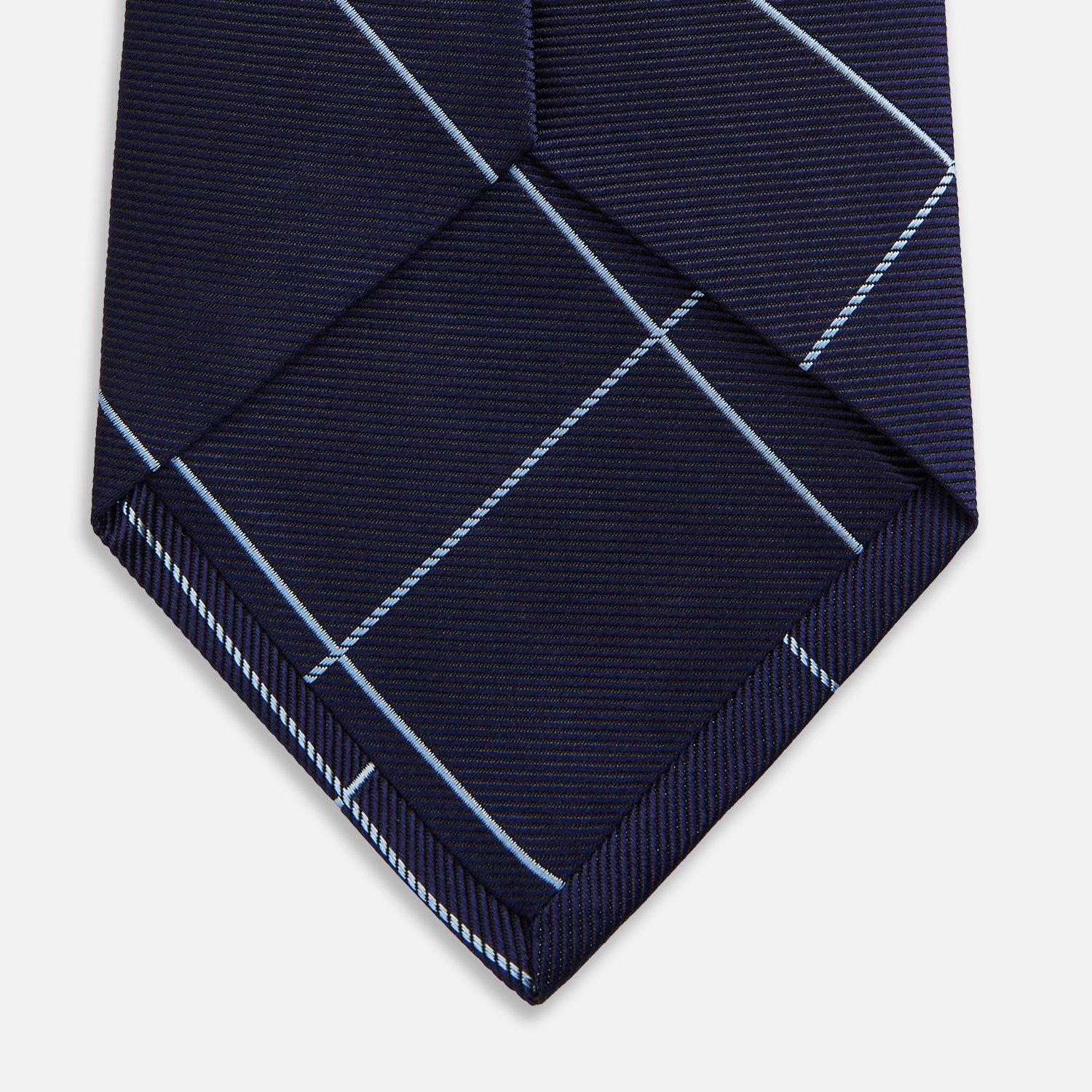 View 4 of product The Turnbull & Asser WINDOW PANE NAVY RIVER TIE features a navy blue base with a subtle light blue check pattern, elegantly rolled on a white background—a sophisticated men's accessory for any wardrobe.