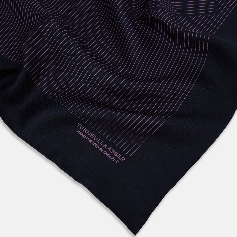 A navy silk pocket square with thin, even purple stripes and hand-rolled edges from Turnbull & Asser, featuring "Turnbull & Asser Hand Printed in England" printed in the corner.