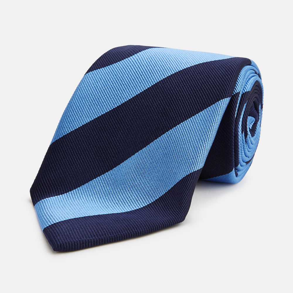 The BLOCK STRIPE NAVY RIVER TIE by Turnbull & Asser features bold navy and light blue diagonal stripes, rolled up neatly on a white background—a stylish essential for elevating any formal look.