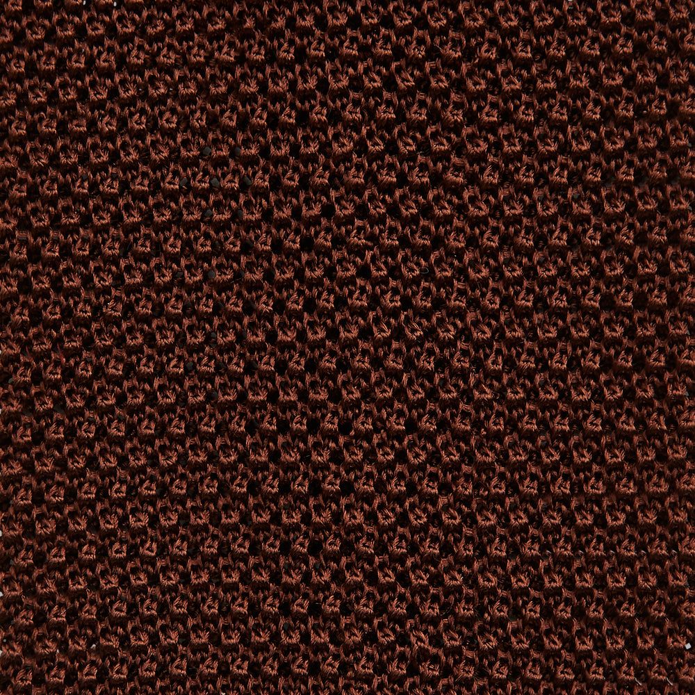 The Turnbull & Asser KNITTED BROWN SILK PLAIN TIE—a stylish, textured accessory—appears rolled up on a white background, perfect for elevating smart outfits.