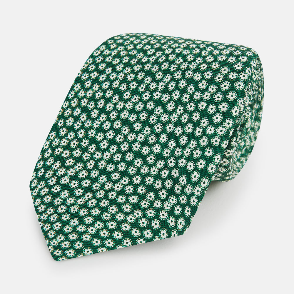 The Forest Green Flower Patterned Silk Tie by Turnbull & Asser features a white floral motif on silk, shown neatly rolled against a plain white background.