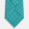 View 3 of product The Turnbull & Asser Turquoise Medallion Silk Tie features light blue and white circular motifs on fine English silk—an elegant men’s accessory, rolled up and displayed on a white background.