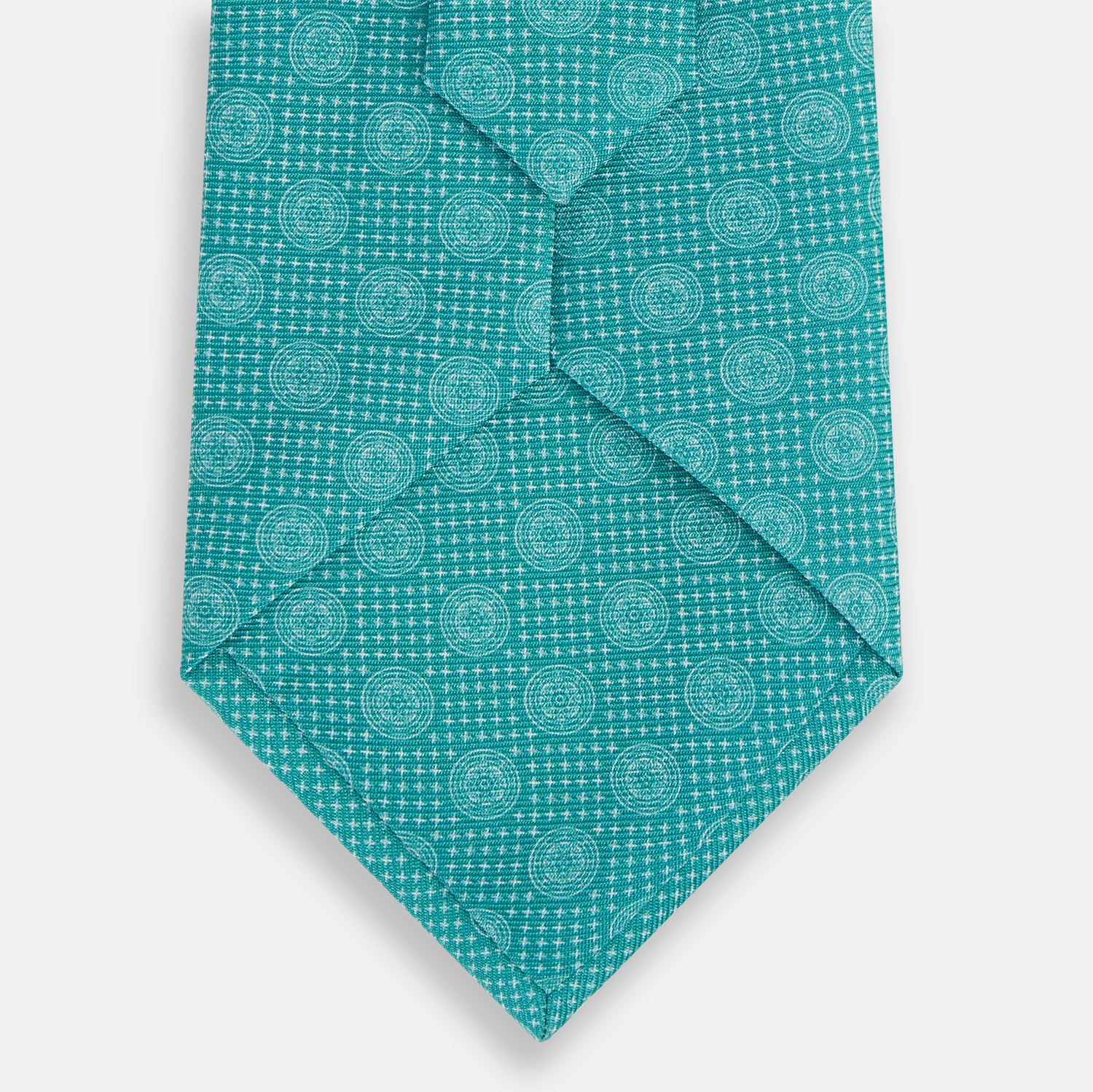 View 3 of product The Turnbull & Asser Turquoise Medallion Silk Tie features light blue and white circular motifs on fine English silk—an elegant men’s accessory, rolled up and displayed on a white background.