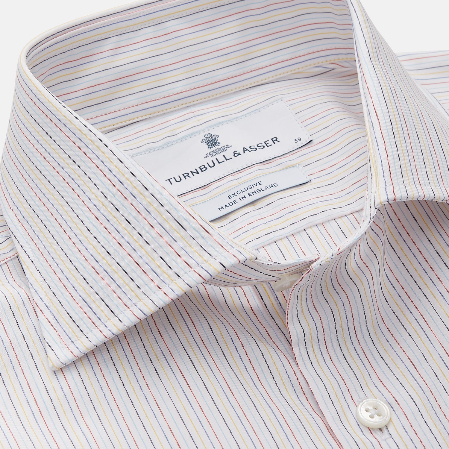 View 2 of product The Turnbull & Asser Red Multi Stripe Tailored Fit Shelton Shirt features subtle vertical stripes, a classic Kent collar, and buttoned cuffs, shown laid flat on a white background.