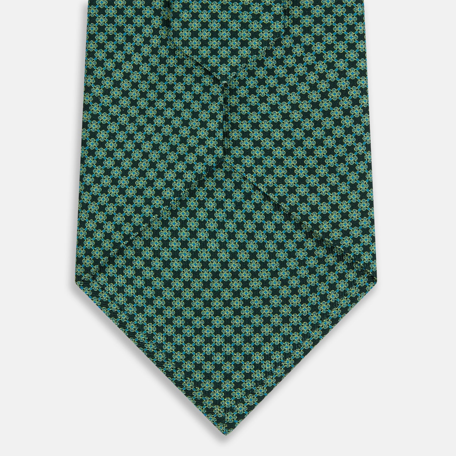 View 3 of product The Turnbull & Asser Forest Green Geometric Floral Silk Tie, showcasing a subtle green and dark blue pattern, is neatly rolled and set against a plain white background.