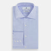 View 5 of product The Turnbull & Asser BLUE HERRINGBONE TAILORED FIT SHIRT WITH KENT COLLAR features long sleeves and buttoned cuffs, offering a timeless formal look in a classic light blue herringbone fabric, laid flat on a white background.