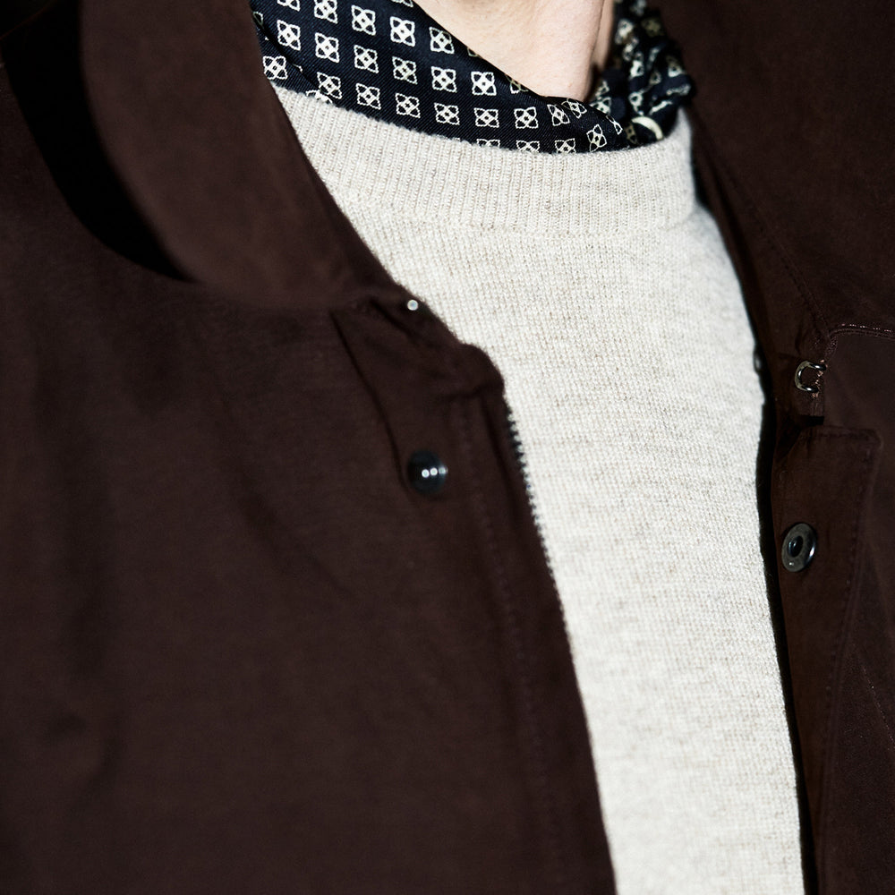 The Burgundy Grayson Car Coat by Turnbull & Asser, made from a rain-resistant cotton blend with a collar, hidden front buttons, and slanted pockets, is displayed flat on a white background in a minimalist style.