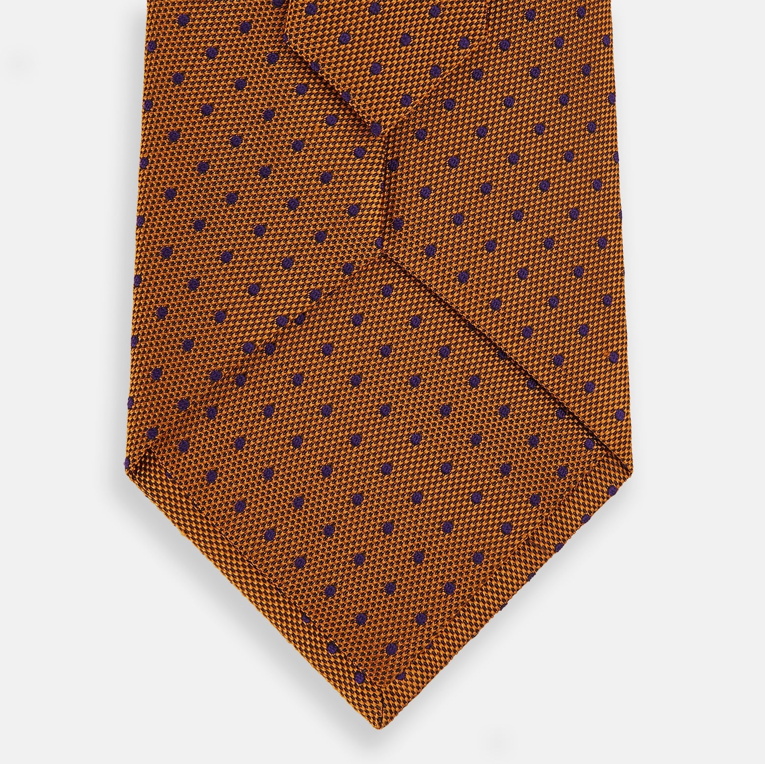 View 3 of product The Turnbull & Asser Purple and Orange Micro Dot Silk Tie, featuring a vibrant polka dot pattern, makes a bold men's accessory and is shown rolled up on a white background.