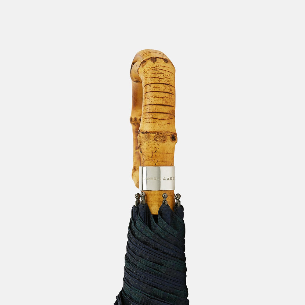 The Turnbull & Asser Black Watch Tartan Telescopic Umbrella features a classic dark green and blue plaid design with a whangee crook handle, highlighting the brand’s renowned craftsmanship against a plain white background.