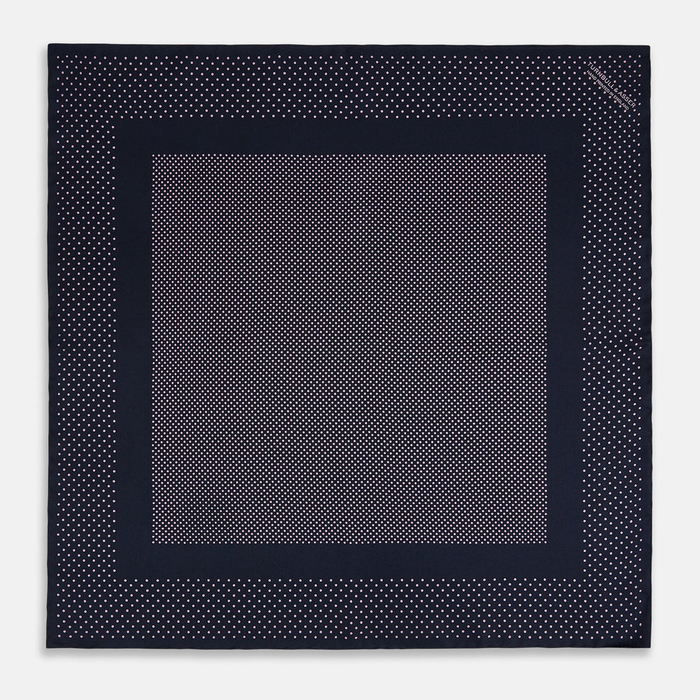 The Turnbull & Asser Navy and Lilac Dot Silk Pocket Square features small white polka dots with a wider border of spaced-out dots, neatly folded to showcase both sides of its handmade silk fabric.