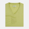 View 4 of product The Turnbull & Asser Melon Green Cashmere V-Neck Jumper features long sleeves with ribbed cuffs and hem, shown against a plain white background.
