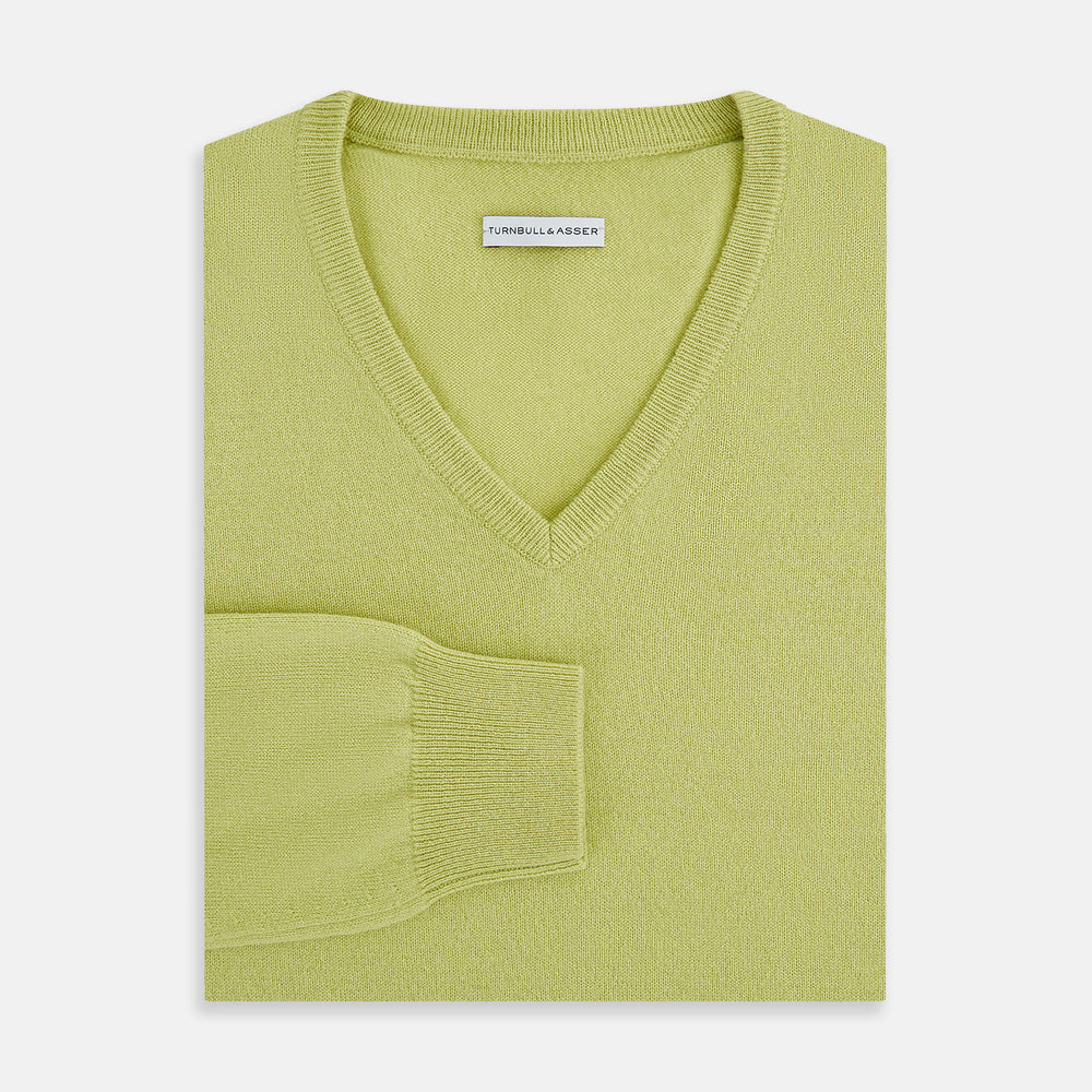 The Turnbull & Asser Melon Green Cashmere V-Neck Jumper features long sleeves with ribbed cuffs and hem, shown against a plain white background.