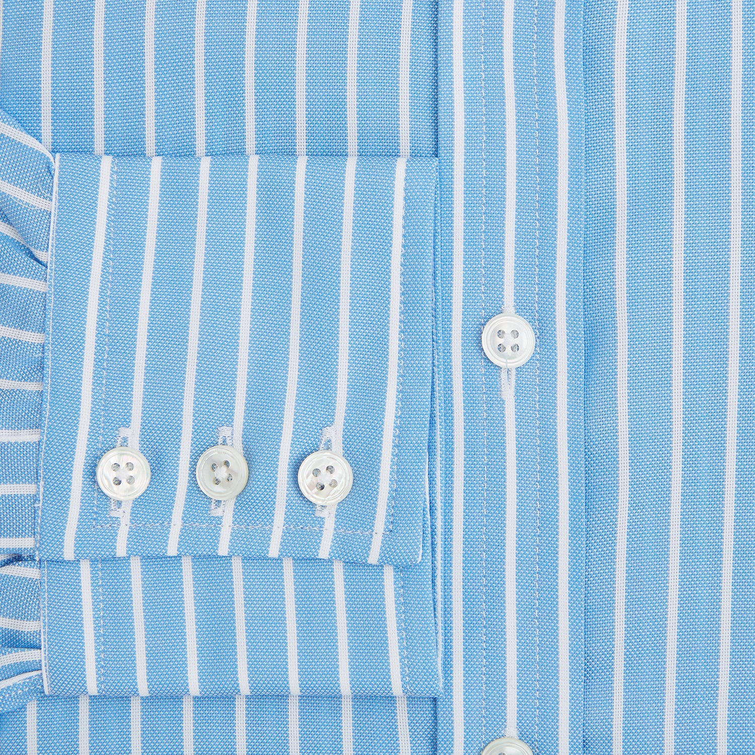 View 4 of product The Turnbull & Asser Sky Blue Wide Pinstripe Mayfair Shirt features long sleeves, a classic collar, and buttoned cuffs, laid flat against a white background for a refined formal look.
