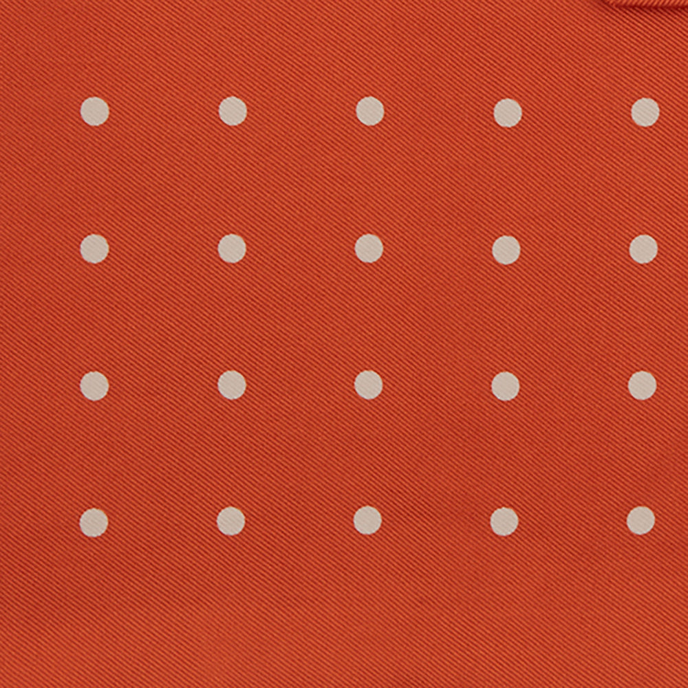 The Orange Spot Silk Pocket Square by Turnbull & Asser features evenly spaced white polka dots and the brand’s name in one corner, making this dapper accessory a standout addition to any outfit.