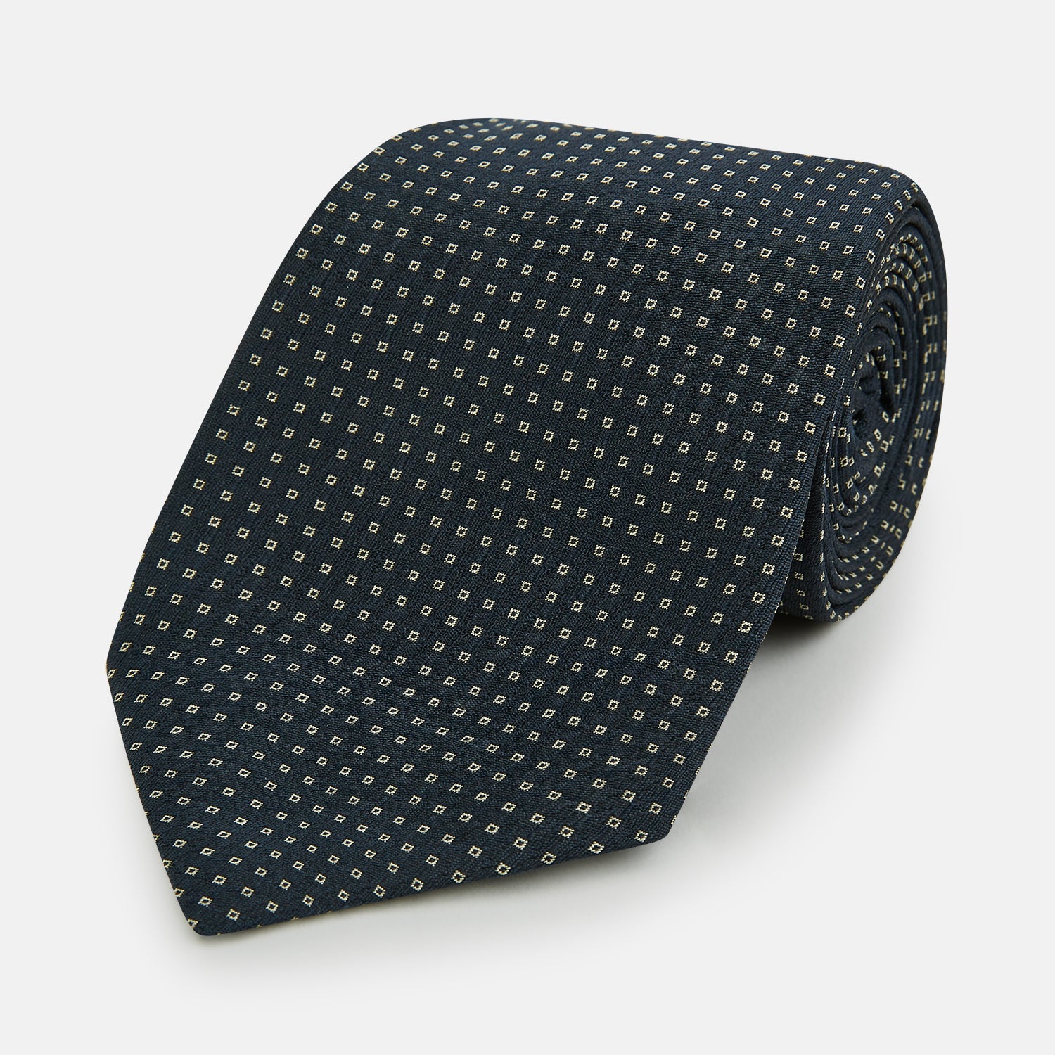 View 1 of product The Navy and White Square Silk Tie by Turnbull & Asser is crafted from English silk with a subtle white square pattern, rolled tip-forward and displayed on a white background for a tailored look.