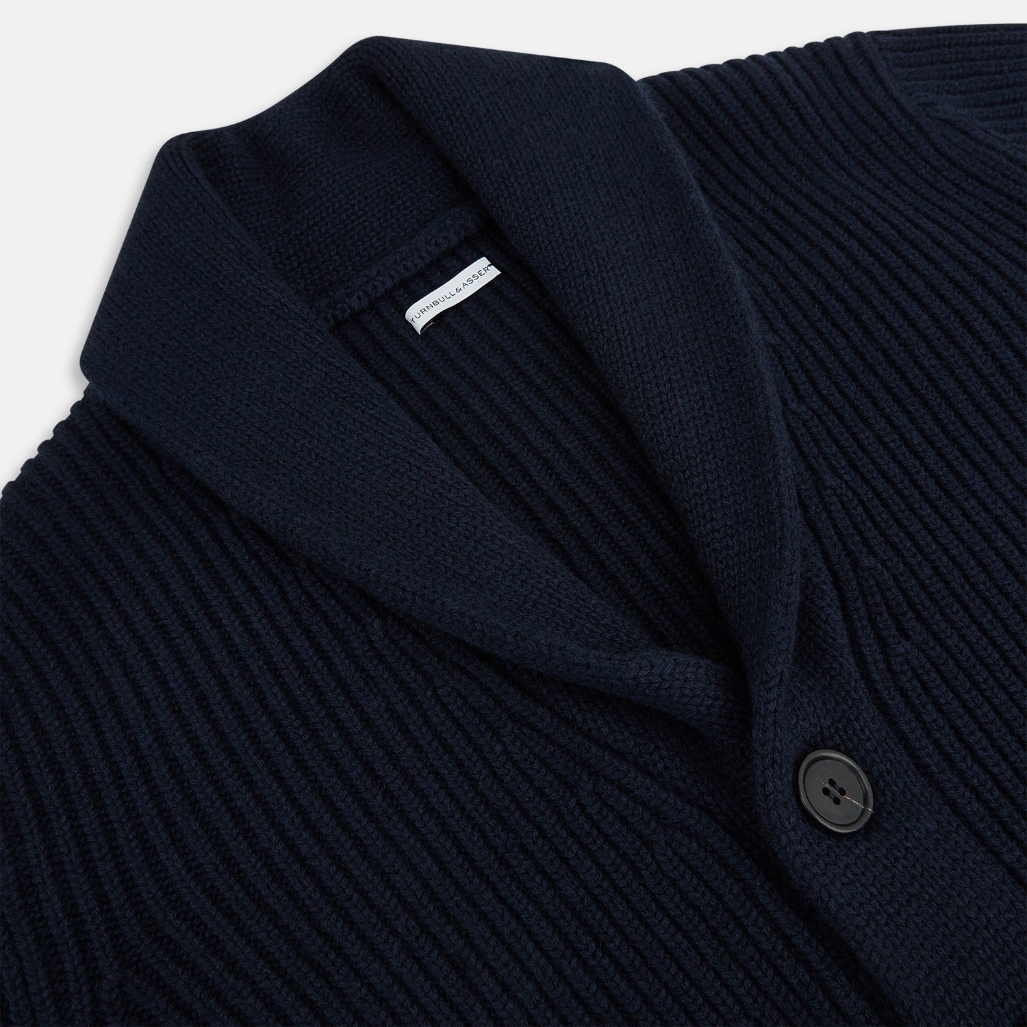 View 2 of product The Turnbull & Asser Midnight Blue Cashmere Shawl Collar Cardigan features ribbed fabric, five black front buttons, a shawl collar, and two front patch pockets, shown against a plain light background.