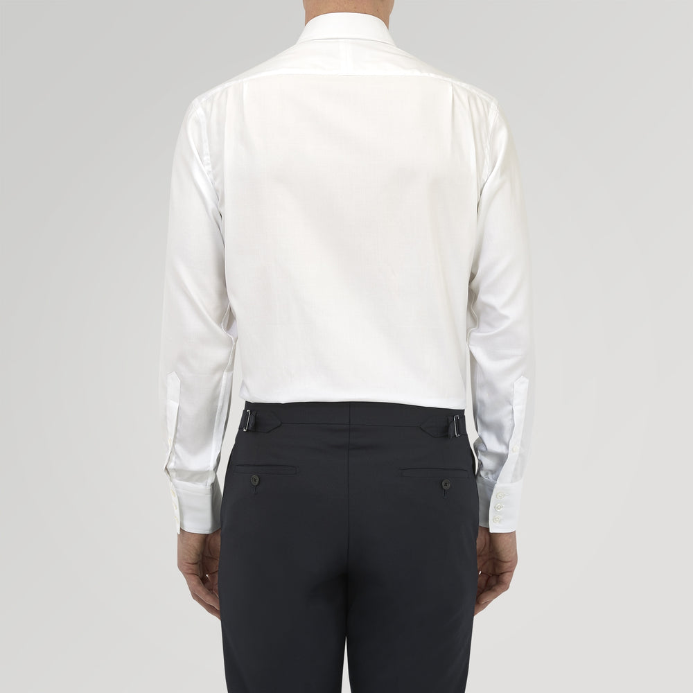 A neatly folded White Sea Island Quality Cotton Twill Shirt by Turnbull & Asser, featuring a T&A collar and 3-button cuffs, is displayed on a light grey background with a label visible inside the collar.