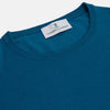 View 3 of product A man with light skin and short brown hair stands against a plain background, wearing the Turnbull & Asser Ocean Blue Merino Kingston Crew Neck Jumper and cream-colored pants, looking directly at the camera with a neutral expression.