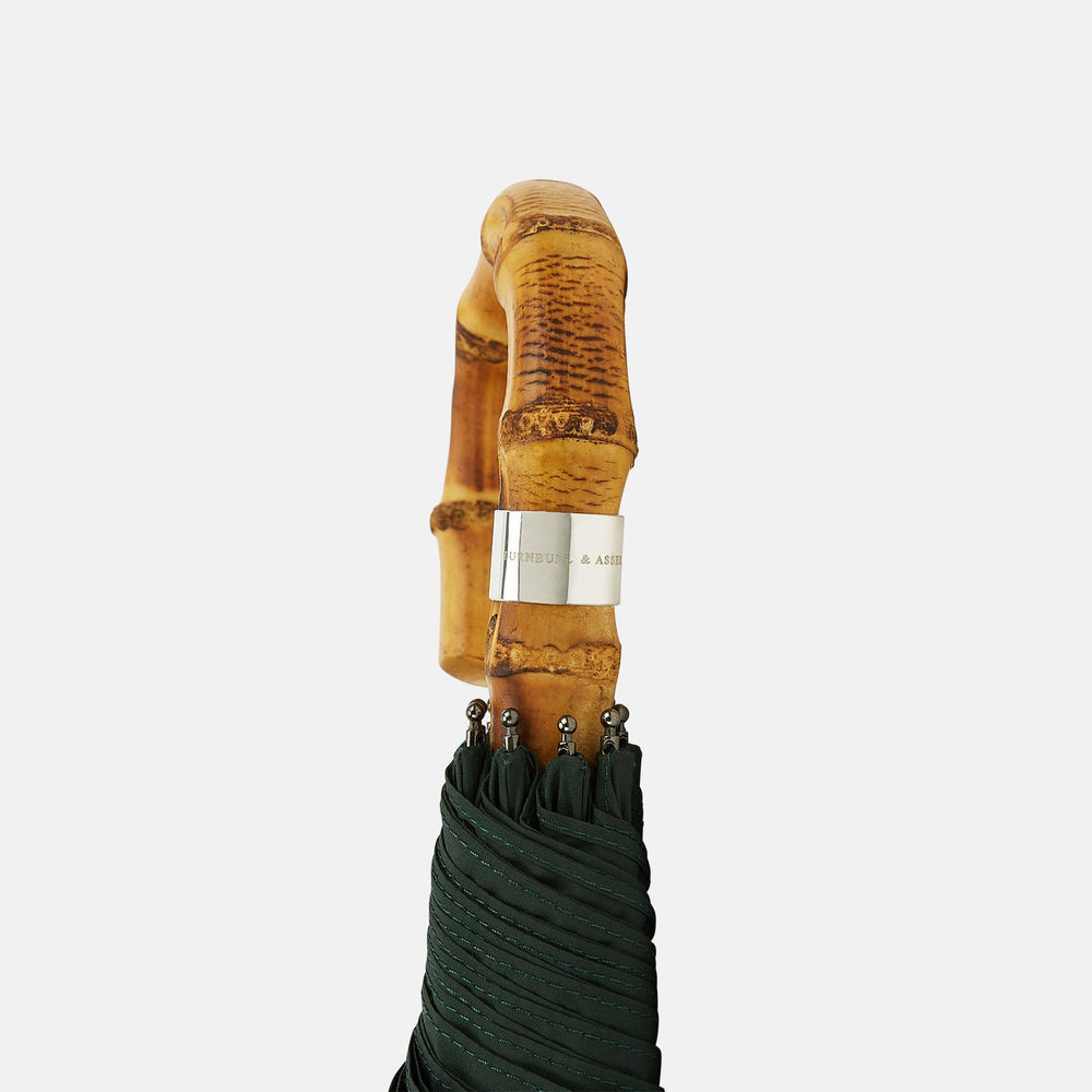 The Turnbull & Asser Forest Green Telescopic Umbrella with a whangee crook handle is opened and displayed on a plain white background, highlighting its expert craftsmanship and timeless style.