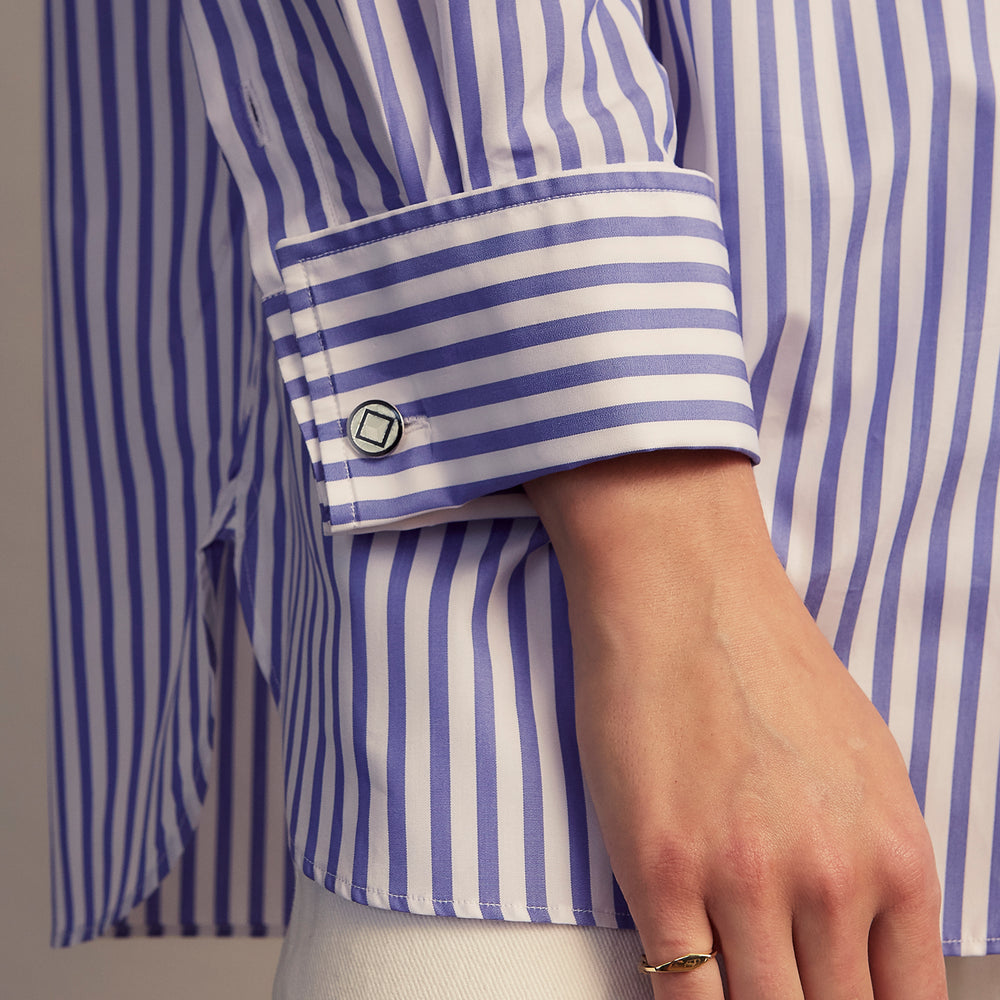 The Turnbull & Asser Pale Blue Candy Stripe Cotton Marlene Shirt is an oversized women's collared shirt with long sleeves, buttoned cuffs, and vertical blue and white stripes, shown laid flat on a white background.