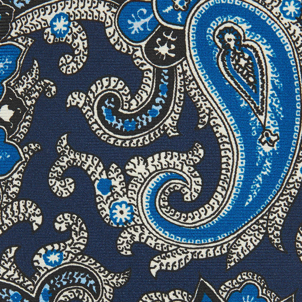 The Turnbull & Asser Blue and Navy Twisted Paisley Silk Tie displays intricate blue, white, and black details, rolled up against a plain white background.