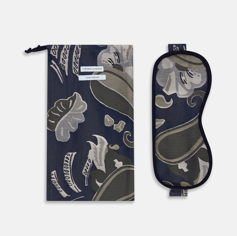 The Turnbull & Asser Navy Bloomsbury Jacquard Cashmere Lined Sleep Mask and Bag features a dark blue backdrop with beige, olive green, and gray floral patterns, plus elastic straps for comfort.