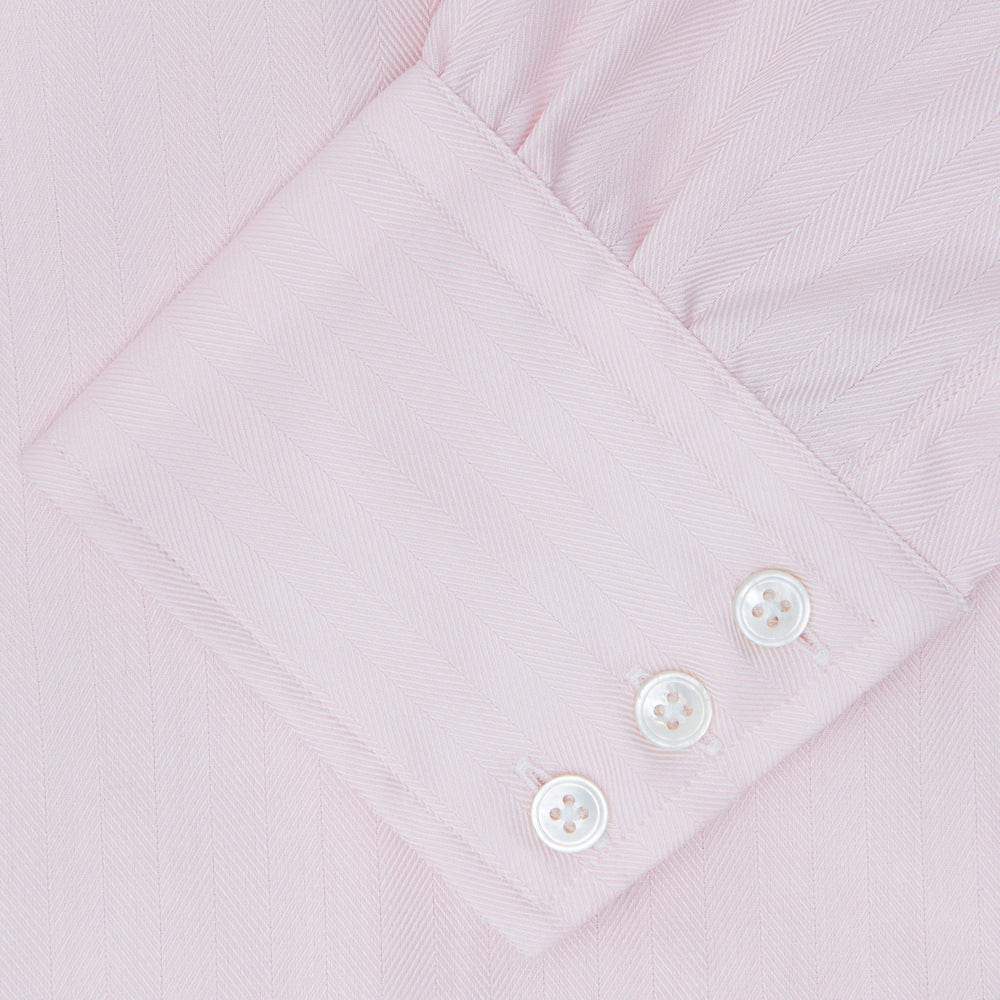 A Pink Herringbone Superfine Cotton Shirt by Turnbull & Asser, featuring a T&A collar and 3-button cuffs, is neatly folded with the inner collar label visible and white buttons, set against a plain white background.
