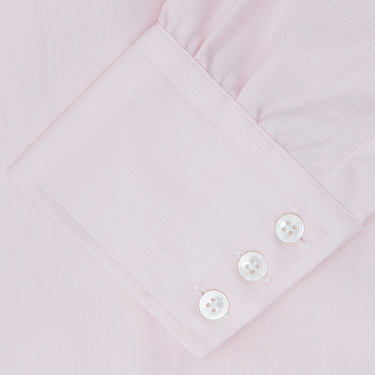 View 6 of product A Pink Herringbone Superfine Cotton Shirt by Turnbull & Asser, featuring a T&A collar and 3-button cuffs, is neatly folded with the inner collar label visible and white buttons, set against a plain white background.