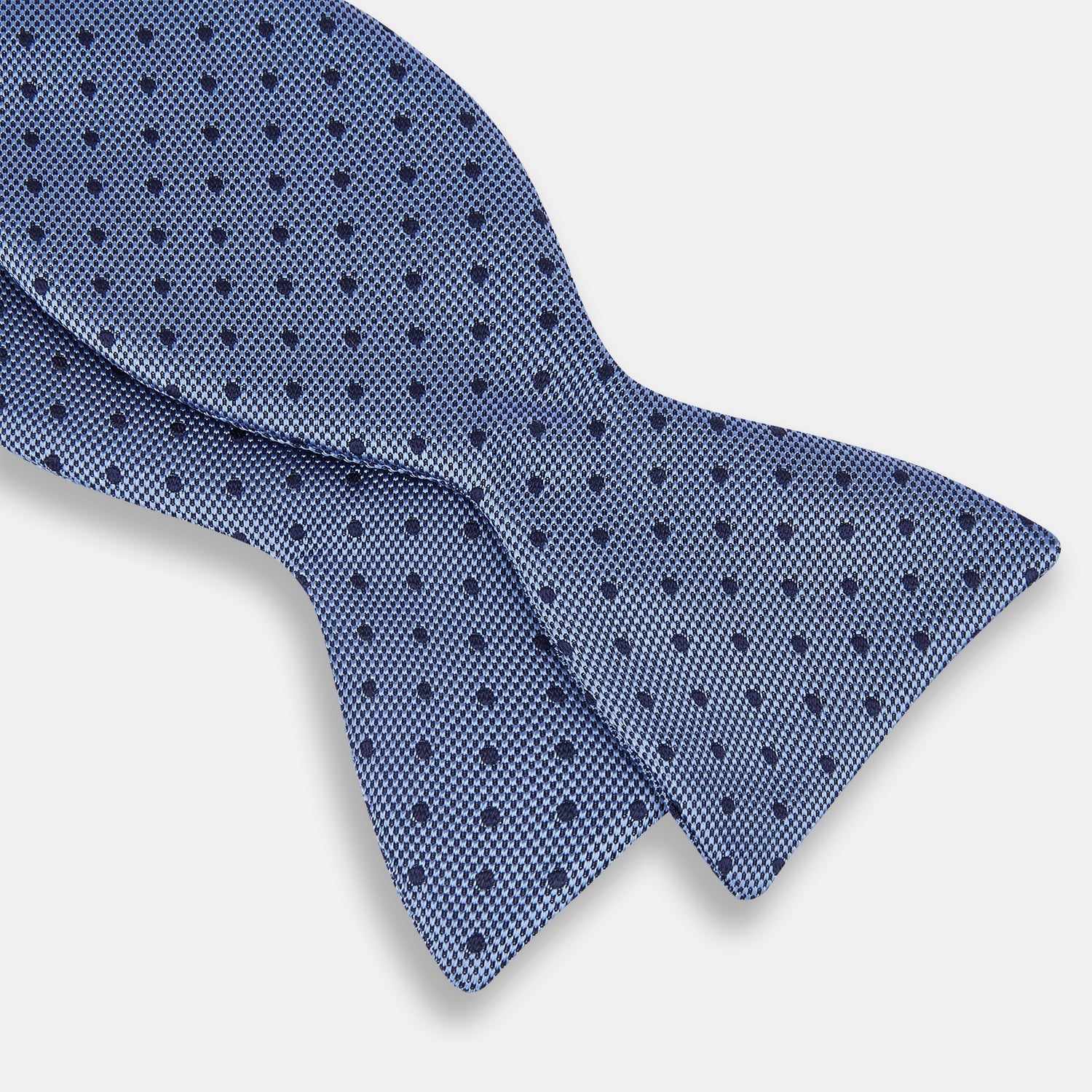 View 3 of product The Turnbull & Asser Blue Micro Dot Silk Bow Tie features a subtle textured pattern with small navy polka dots, shown on a white background—an ideal accessory for smart attire.