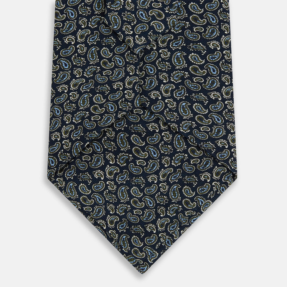 The Turnbull & Asser Navy Paisley Foulard Silk Tie features a refined paisley pattern in blue, white, and beige tones, elegantly rolled and presented against a white background.