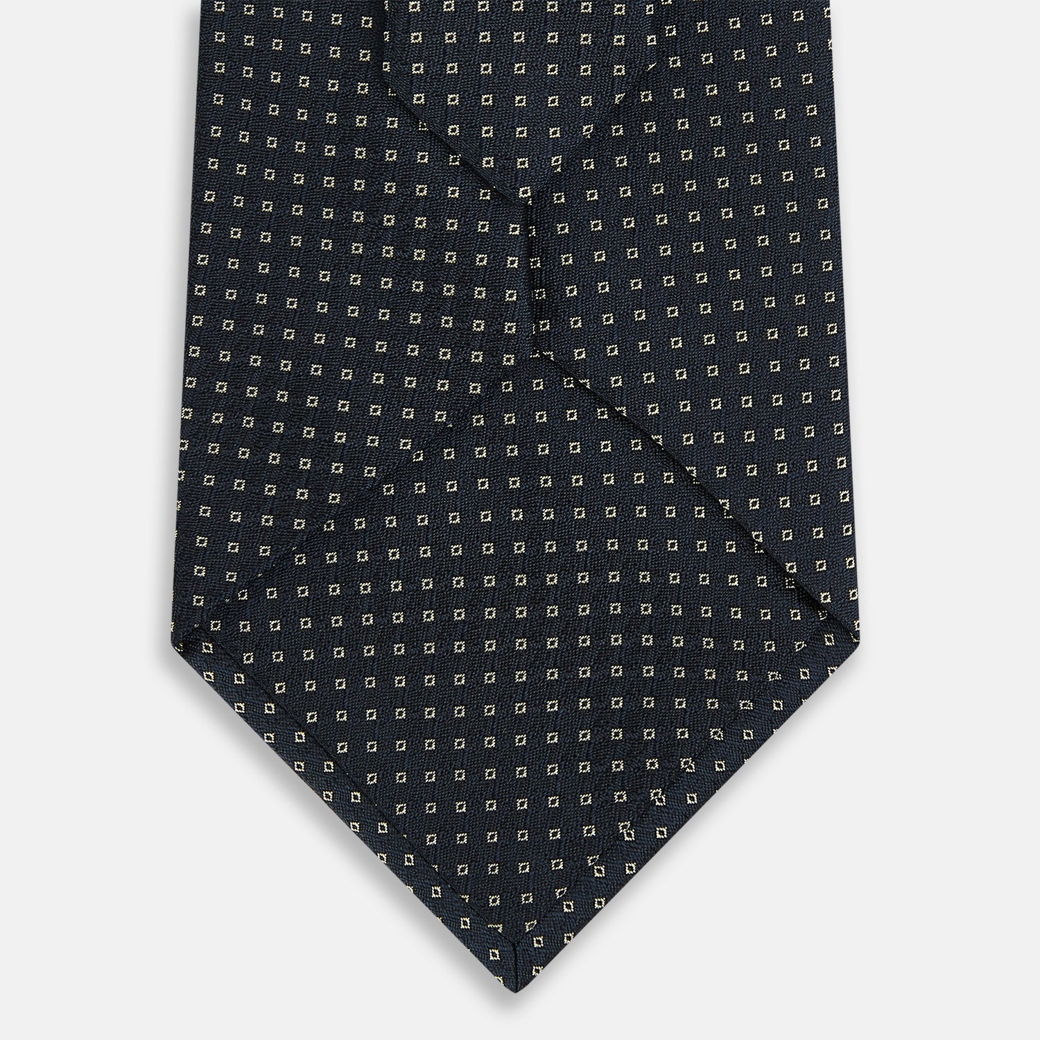 View 3 of product The Navy and White Square Silk Tie by Turnbull & Asser is crafted from English silk with a subtle white square pattern, rolled tip-forward and displayed on a white background for a tailored look.
