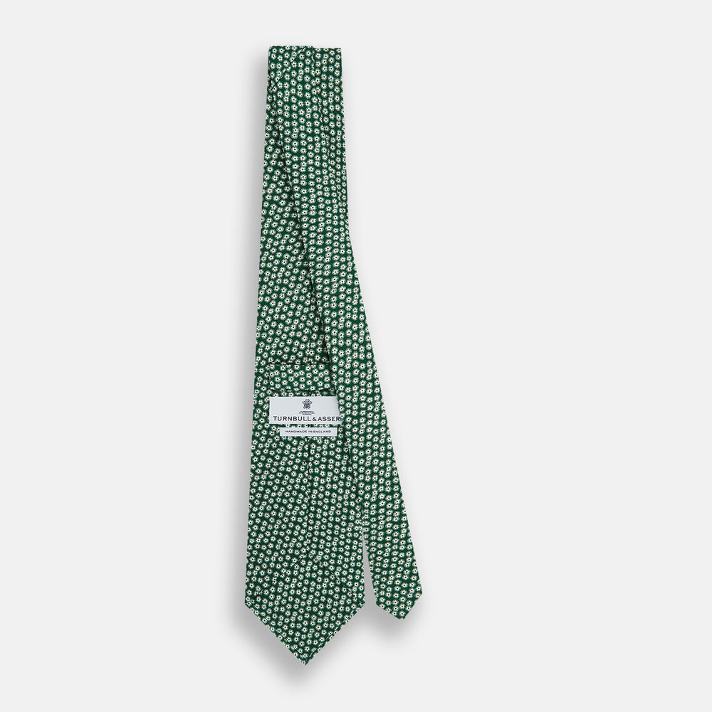 The Forest Green Flower Patterned Silk Tie by Turnbull & Asser features a white floral motif on silk, shown neatly rolled against a plain white background.