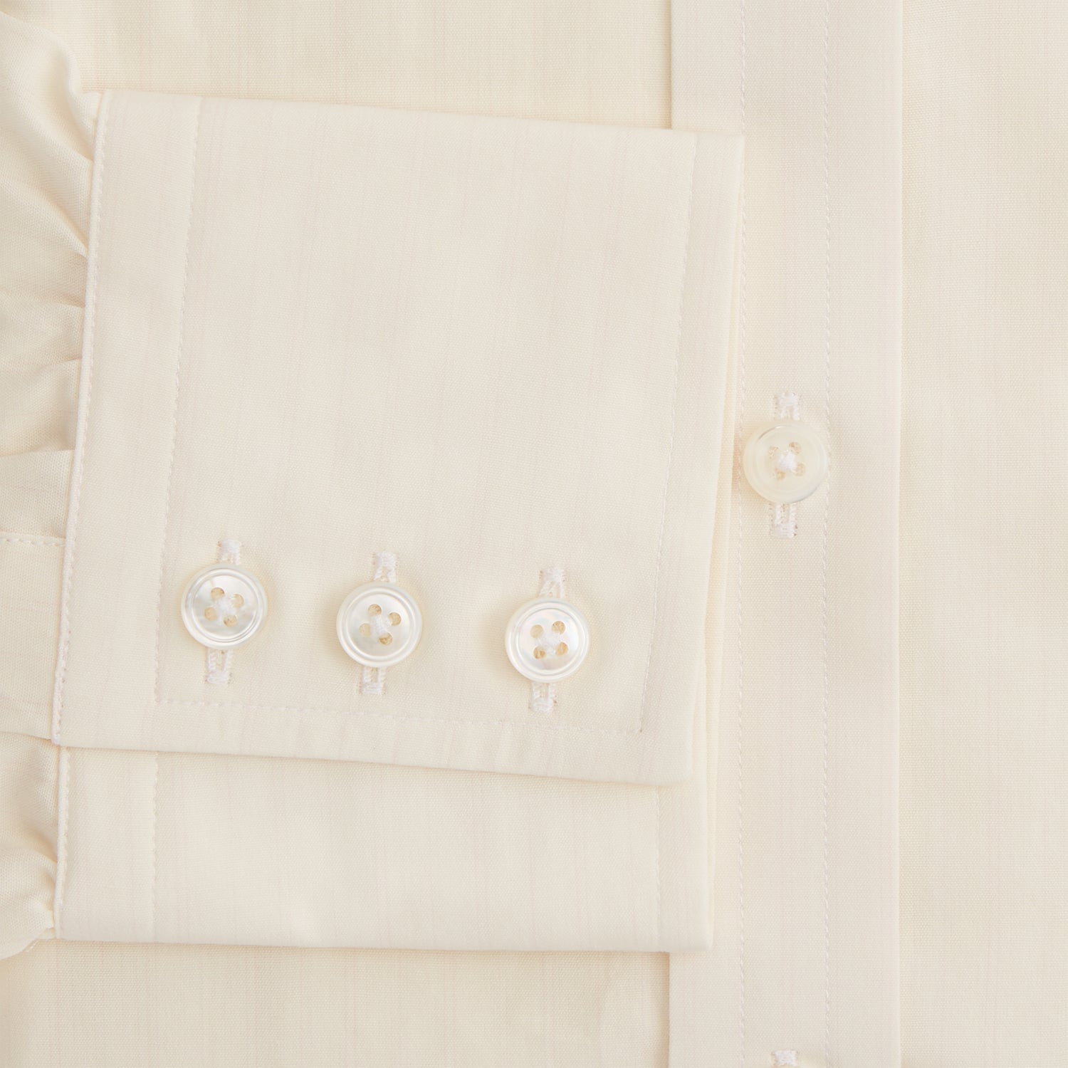 View 4 of product The Cream Fine Pencil Stripe Mayfair Shirt by Turnbull & Asser features long sleeves, a pointed collar, and buttoned cuffs. Crafted from breathable cotton with fine pencil stripes, it is shown laid flat on a white background.