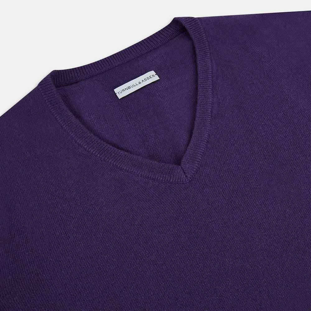 The Turnbull & Asser Purple Cashmere V-neck Jumper features long sleeves with ribbed cuffs and hem—a classic knitwear piece for effortless layering, shown against a white background.