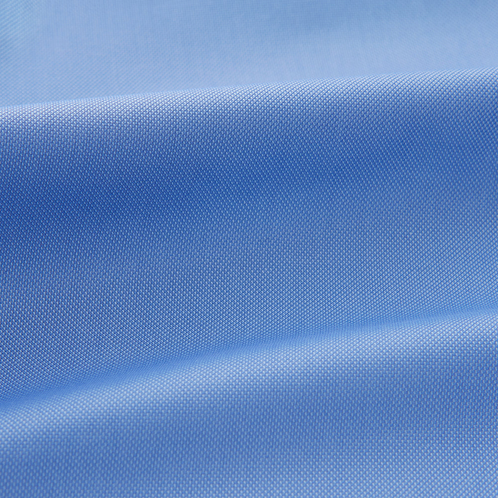 The Turnbull & Asser "The World Is Not Enough" blue cotton Istanbul shirt, as seen on James Bond, is a light blue oxford long-sleeve button-up with a pointed collar and white buttons, displayed on a white background.