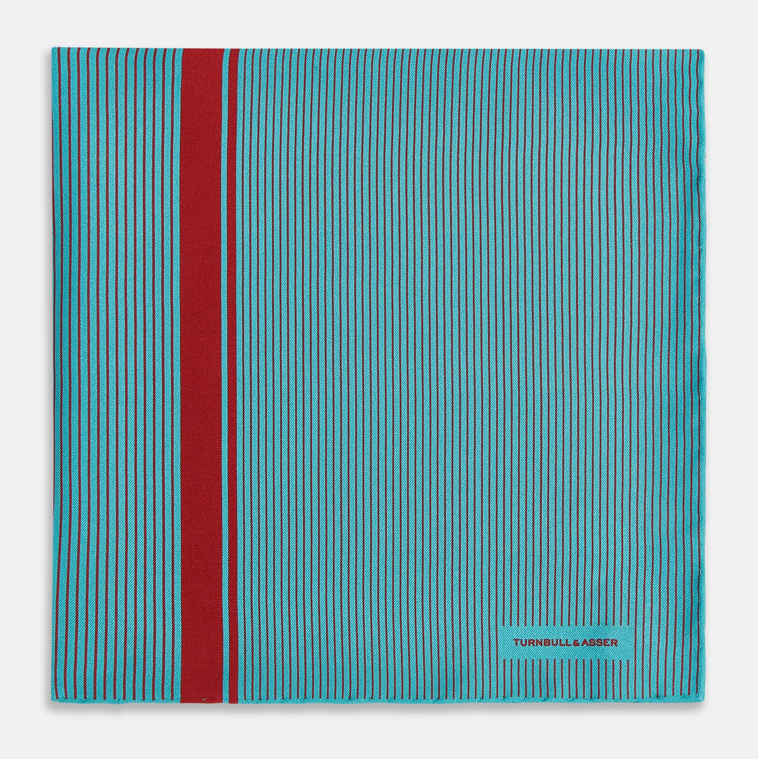 View 3 of product The Turnbull & Asser Turquoise and Red Stripe Silk Pocket Square features thin navy stripes with a bold vertical red stripe, partially folded to reveal the reverse pattern and the brand's logo, showcasing its British heritage.